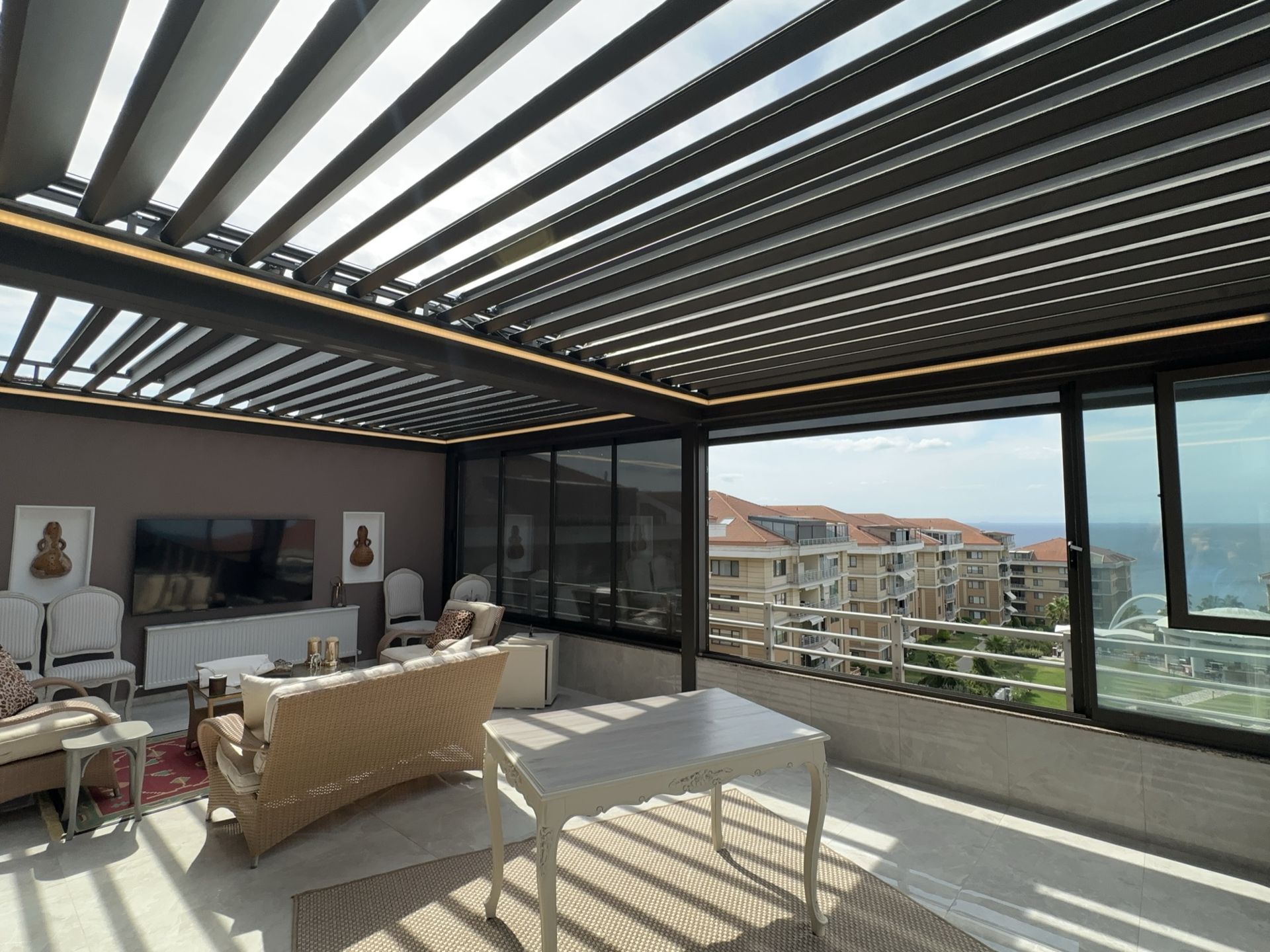 Lamelleri açık bioklimatik pergola altında deniz manzaralı teras